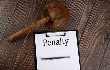PENALTY text on the paper with gavel on the wooden background