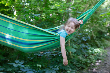 Wall Mural - Cute little girl laughing while lying in hammock