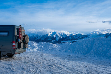 Wall Mural - Dirty 4x4 camper van in snowy landscape with incredible clouds behind