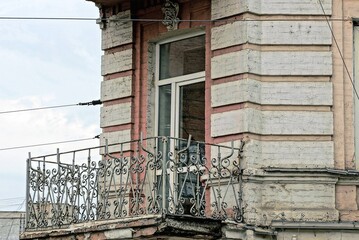 Sticker - one gray metal open balcony with wrought iron pattern on the brown concrete wall of an old house