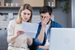 © Liubomir - Man and woman, young family together intently reading a letter, frustrated