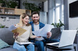 © Liubomir - Happy married couple, man and woman, received a positive letter, sitting at home on the couch, smiling and rejoicing