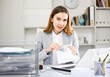 © JackF - Portrait of happy woman sitting at working place in office and receiving bonus or salary or money in envelope