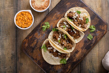 Pork Carnitas Tacos With Onion And Cilantro Served With Rice And Refried Beans