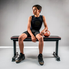 Wall Mural - Male youth football player sitting on bench in a relaxed pose