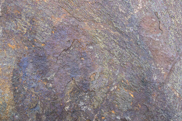 Rough cut rock in dark colors of gray and purple, as a natural  background
