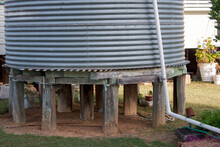 Old Corrugated Iron Water Tank In Yard With Wooden Stumps