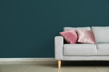 Modern sofa with pillows near color wall in room