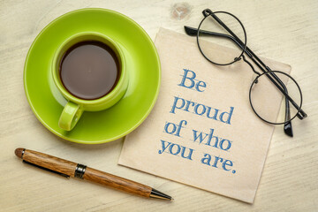 Wall Mural - Be proud of who you are inspirational handwriting on a napkin with a cup of coffee, success and personal development concept