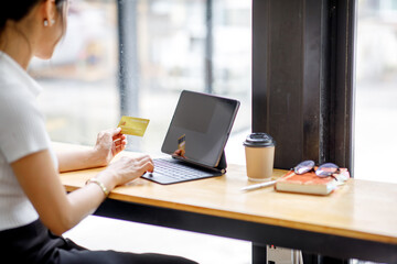 Women holding credit card and using tablet laptop computer at coffee shop.Online shopping, internet banking, store, payment, spending money, e-commerce payment at the store, credit card, concept