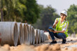© kamonrat - Woman construction site engineer architect worker with hard hat using tablet for checking concret pipes