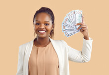 Studio Shot Of Beautiful Rich Woman Standing On Beige Color Background, Smiling And Holding Lots Of Cash. Black Lady Earns First Money With Her Own Business. Happy Girl Shows Off Her Passive Income