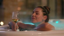 Young Woman Enjoying In Bubble Bath With Glass Of Champagne