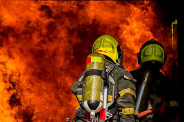 firefighters wearing fire fighter suit for safety and using twirl water extinguisher for fighting the fire flame in emergency situation.. - Safety Firefighter and industrial concept.