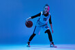 Portrait of teen girl, basketball player in motion, dribbling ball isolated over white studio background. Active game