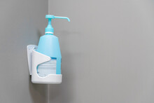 Close-up of a blue bottle with disinfectant on a light wall, copy space.