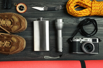 Wall Mural - Flat lay composition with different camping equipment on dark wooden background. Traveler set