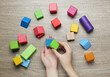 ABA therapist with colorful building blocks at wooden table, top view
