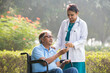 Female doctor discussing with senior man in wheelchair at park