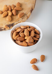 Wall Mural - Almonds in white bowl on white background.