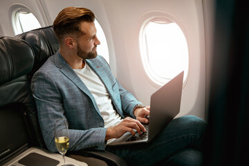 Male passenger working on laptop in airplane