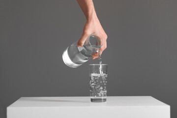 person holds a bottle and pour water in the glass