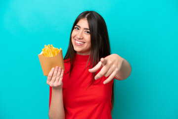 Young caucasian woman catching french fries isolated on blue background pointing front with happy expression