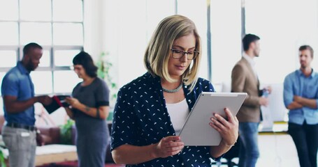 Poster - Shes the glue of the company. 4K video footage of a young woman using a digital tablet while standing in a modern office with coworkers in the background.
