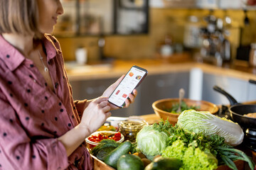 young housewife shopping groceries online on mobile phone, close-up on phone screen with e-shop and 