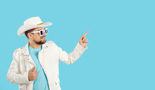 Check It Out, Guys. Happy Handsome Bearded Young Man Wearing Casual Outfit, Hat And Sunglasses Standing On Blue Studio Background And Pointing To Empty Copy Space On Right Side. Sale, Discount Concept
