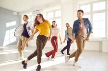 Group Of Happy Beautiful Young People Enjoying A Contemporary Dancing Class. Team Of Cheerful Smiling Dancers In Casual Wear Practising A New Choreo And Having A Good Time Together In A Modern Studio