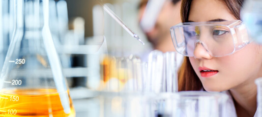 Canvas Print - Attractive scientist woman looking chemical sample in flask at laboratory with lab glassware background. Science or chemistry research and development concept.