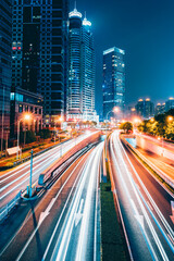 Buildings in the night view of the city and cars driving on the expressway