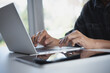 © tippapatt - Businessman working laptop computer, surfing the internet with digital tablet on the table at home office. Working at home, telecommuting concept