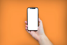 Hand Holding The Black Smartphone With Blank Screen And Modern Frame Less Design On Orange Colour Background