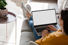 Young Woman Using Laptop Screen Blank, Mockup Lying On Sofa At Home