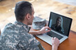 © Angelov - soldier man smiling while making conference call on laptop indoors
