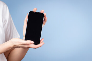 woman holding cell phone in her hand and showing smartphone screen direct to camera. front view