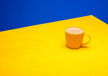 A Yellow Coffee Cup  On Yellow Table On A Blue Background. The Concept Of Minimalism. Place For Text
