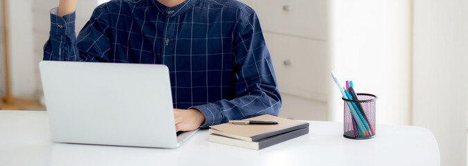 Wall Mural - Happy young businessman work on laptop computer finish with excited and success on desk at home, business man using notebook with achievement and surprised, freelance or employee, satisfied and glad.