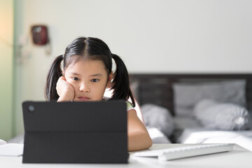 Wall Mural - asian child bored learning by study online class on computer tablet or kid girl student back to school by video call studying and hand to cheek or person learn from home by reading on pad in bedroom