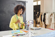 © Friends Stock - Professional African-American fashion designer with conducts online class at table with color palettes