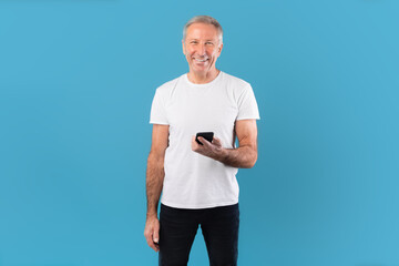 Poster - Happy mature man using his mobile phone at blue studio