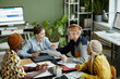 © Seventyfour - Diverse creative team collaborating in business meeting and enjoying work on project together, high angle