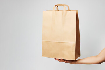 Woman holding brown paper bag on white background