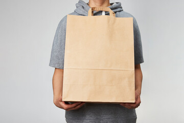 Woman holding brown paper bag on white background