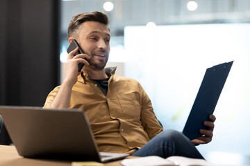 Canvas Print - Successful Businessman Talking On Cellphone Looking At Documents In Office