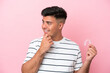 © luismolinero - Young caucasian man holding invisaling isolated on pink background thinking an idea and looking side