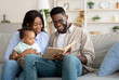 © Prostock-studio - Portrait of happy black family reading book for son