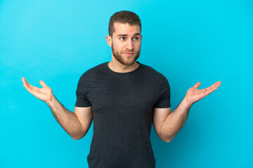 Poster - Young handsome caucasian man isolated on blue background having doubts while raising hands